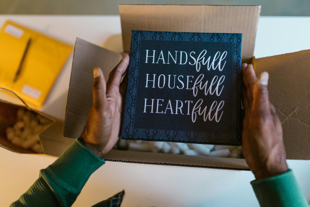 Close-up of hands holding decorative art board from a package with motivational words.